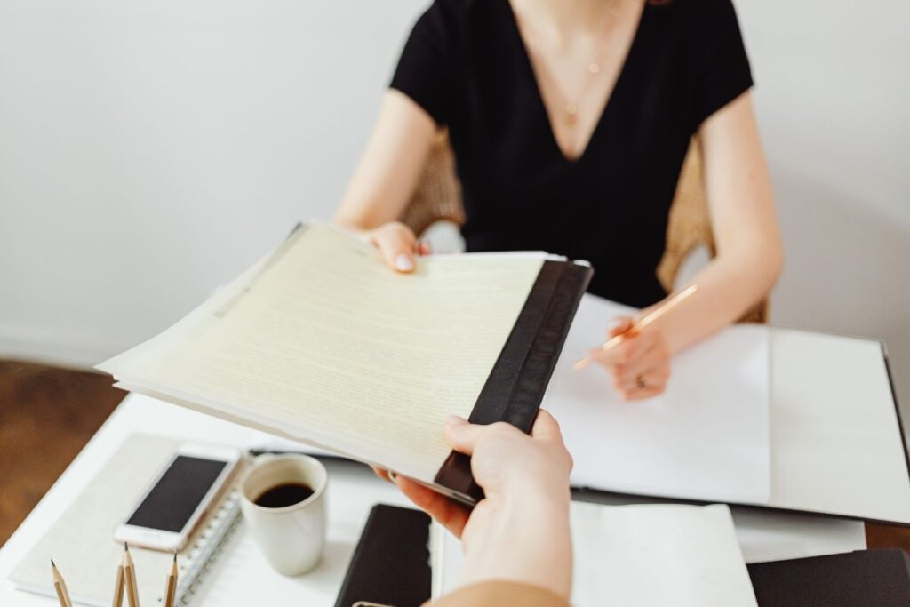 Profissional entregando currículo em entrevista demonstrando preparação para conseguir emprego em 2026