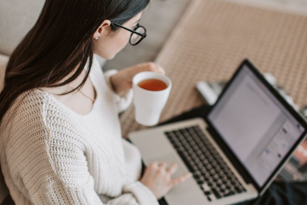 Mulher estudando no notebook com chá desenvolvendo habilidades para conseguir emprego em 2026 em casa
